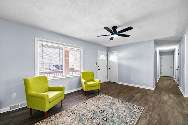 living area featuring dark wood-type flooring, visible vents, a textured ceiling, and baseboards