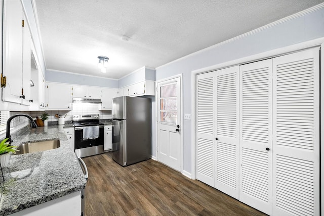 kitchen featuring stainless steel appliances, white cabinets, a sink, dark stone countertops, and under cabinet range hood