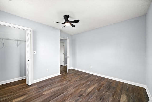 unfurnished bedroom featuring a closet, dark wood finished floors, a ceiling fan, and baseboards