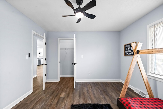 unfurnished bedroom with multiple windows, baseboards, and dark wood-type flooring