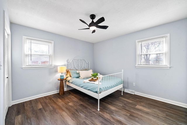 bedroom with dark wood-type flooring, multiple windows, and visible vents