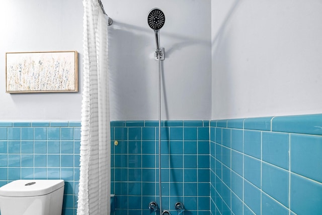 bathroom featuring wainscoting, tile walls, and toilet