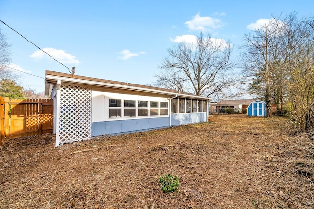 back of house with fence, an outdoor structure, and a storage unit