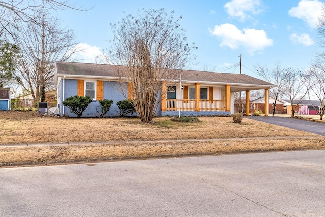 single story home featuring roof with shingles, brick siding, covered porch, a carport, and driveway