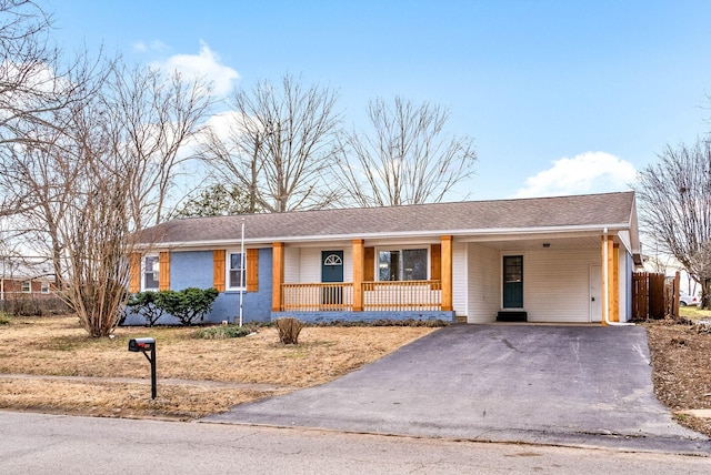 ranch-style home with aphalt driveway, covered porch, and a carport