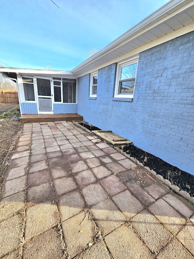 view of patio with fence and a sunroom