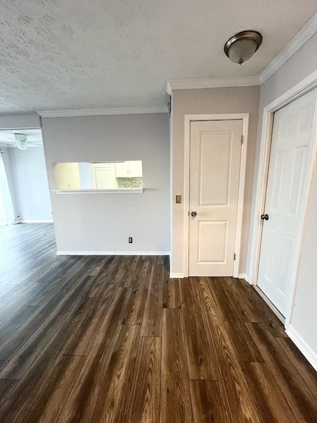 unfurnished room with a textured ceiling, baseboards, dark wood finished floors, and crown molding