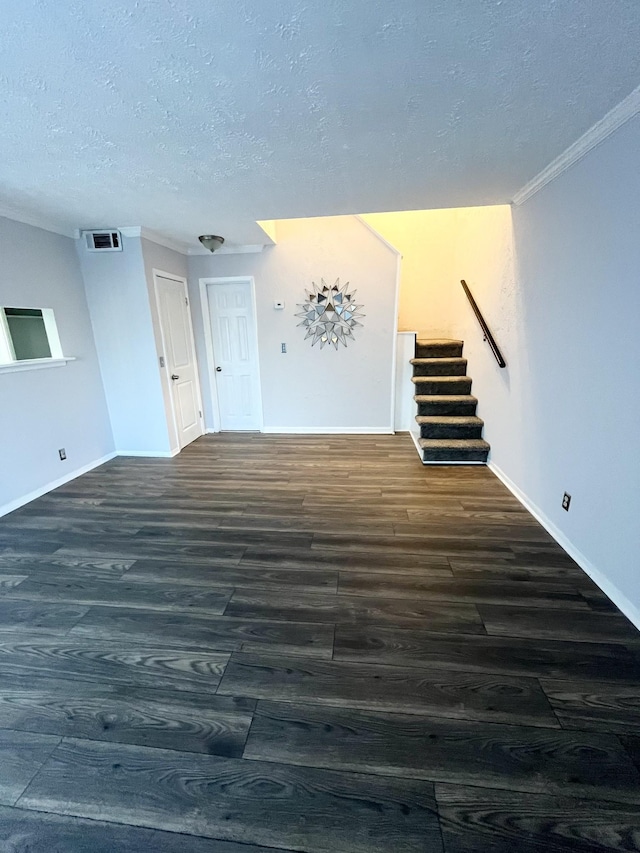 empty room featuring dark wood finished floors, visible vents, stairway, ornamental molding, and a textured ceiling