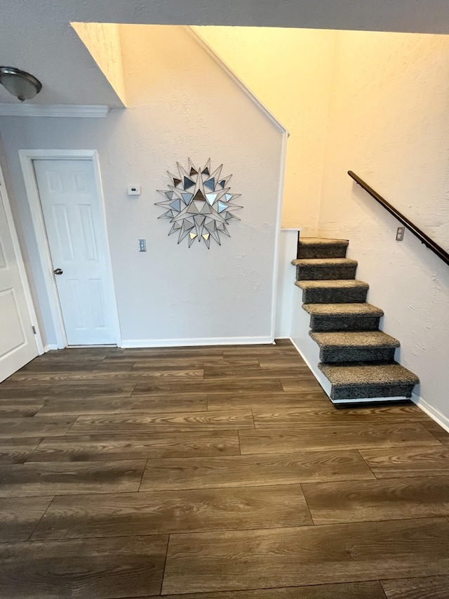 stairway with ornamental molding, baseboards, and wood finished floors