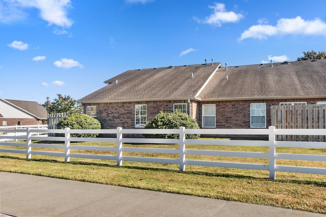 view of home's exterior with a fenced front yard, brick siding, and a shingled roof