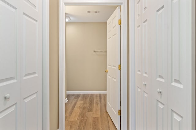 corridor featuring visible vents, light wood-style flooring, and baseboards