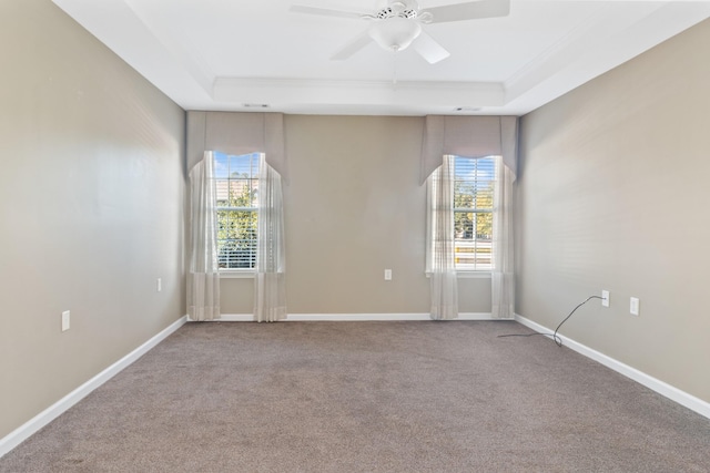 carpeted empty room with ceiling fan, baseboards, a raised ceiling, and ornamental molding