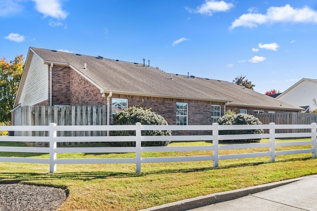 ranch-style home featuring a fenced front yard, a shingled roof, and brick siding