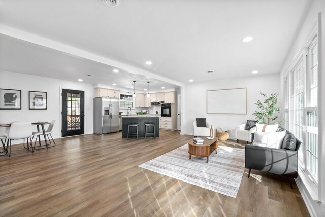 living area with recessed lighting, a healthy amount of sunlight, baseboards, and wood finished floors