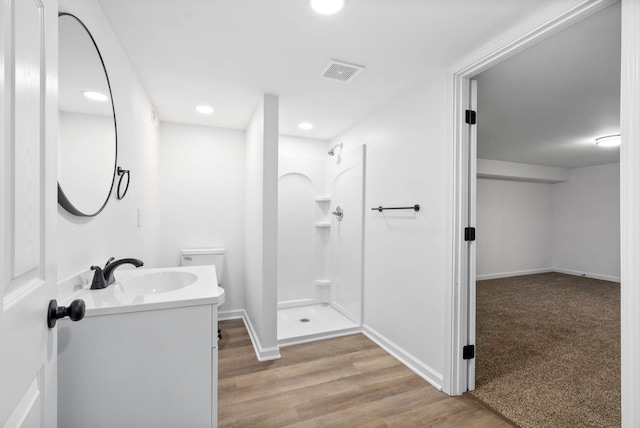 full bathroom with visible vents, vanity, a shower stall, and wood finished floors