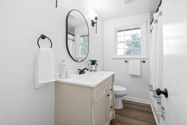 bathroom with visible vents, toilet, vanity, wood finished floors, and baseboards