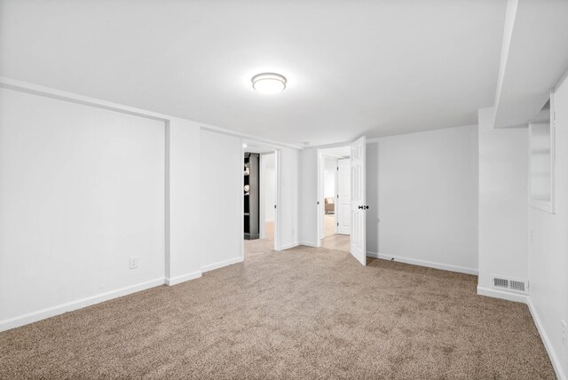 interior space featuring light colored carpet, visible vents, and baseboards