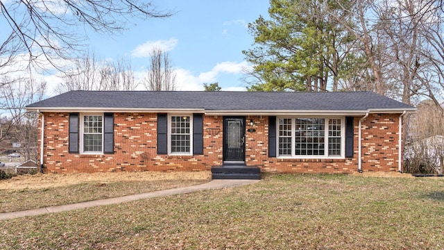 ranch-style home featuring a shingled roof, a front yard, and brick siding