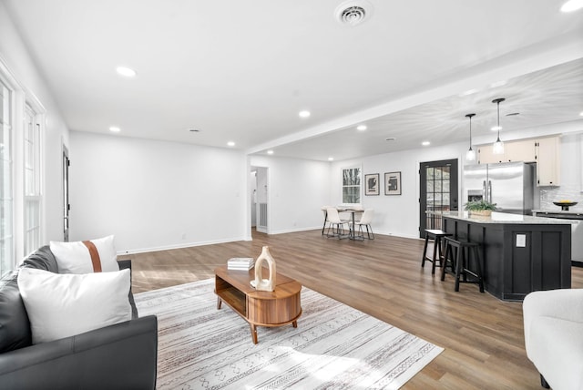 living room featuring light wood-type flooring, visible vents, baseboards, and recessed lighting