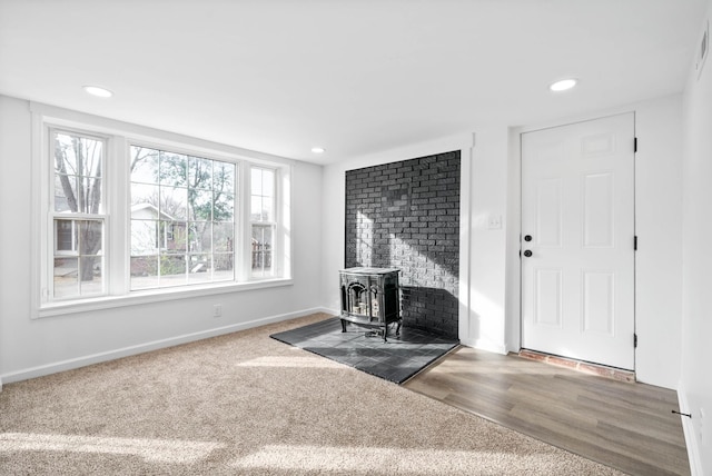 interior space with baseboards, wood finished floors, a wood stove, and recessed lighting