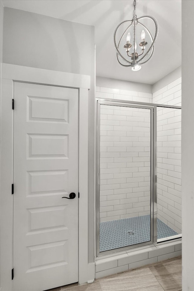 bathroom with a stall shower and an inviting chandelier