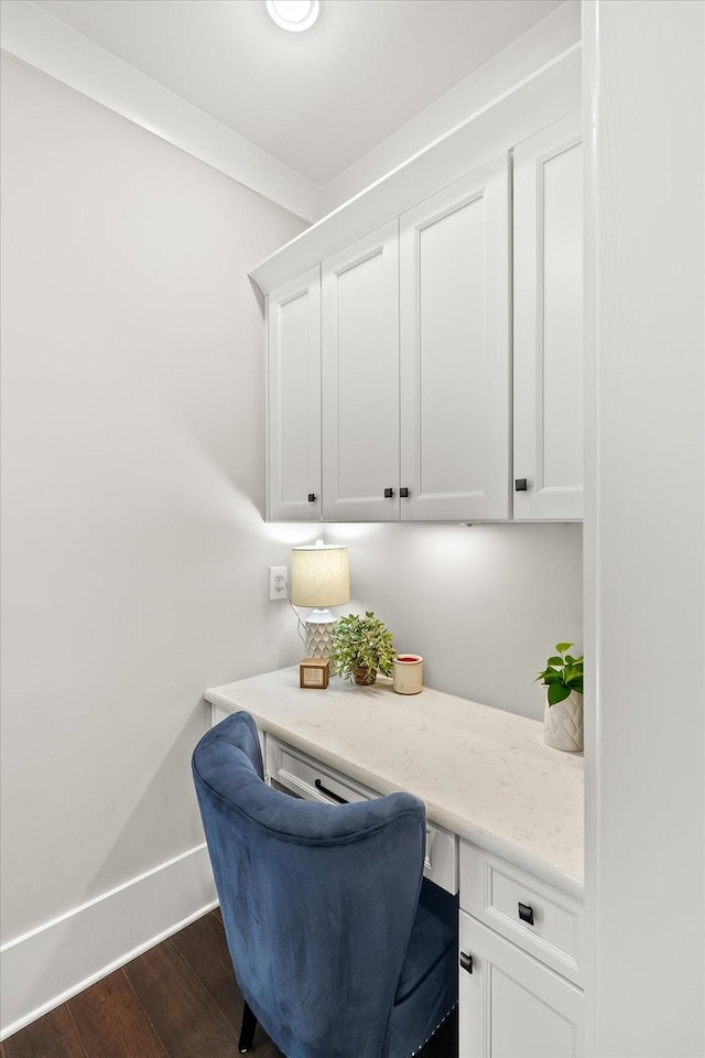 office space featuring built in desk, dark wood-style flooring, and baseboards