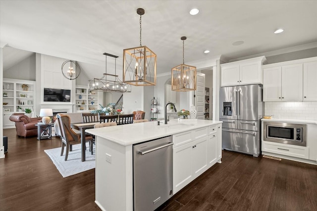 kitchen featuring pendant lighting, light countertops, appliances with stainless steel finishes, open floor plan, and a sink