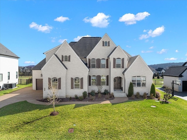 french country inspired facade with driveway, a garage, central AC unit, a front yard, and brick siding