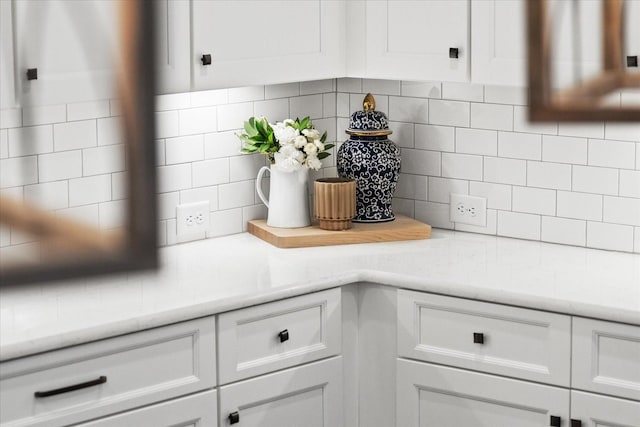 interior details with light stone counters, white cabinets, and backsplash