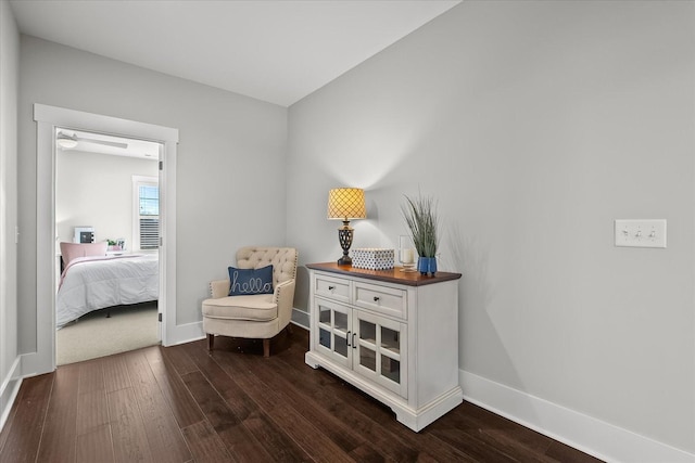 sitting room with baseboards and dark wood-style flooring