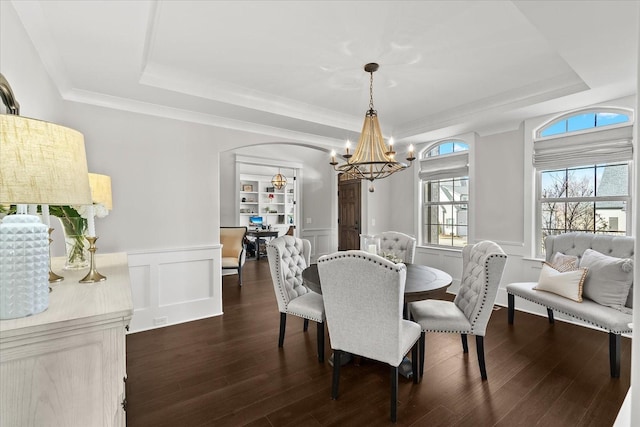 dining area with dark wood-style floors, wainscoting, and a raised ceiling