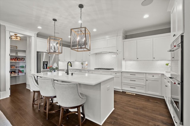 kitchen with a center island with sink, stainless steel appliances, light countertops, white cabinets, and a sink