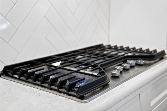 room details featuring white cabinetry, stainless steel gas cooktop, and light countertops