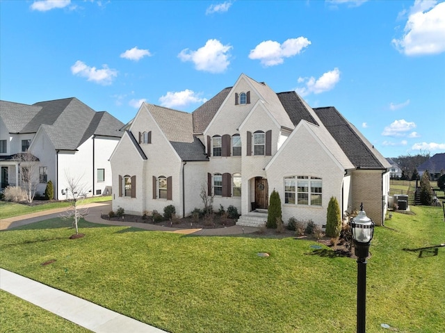 french country inspired facade featuring a front yard, brick siding, and a residential view