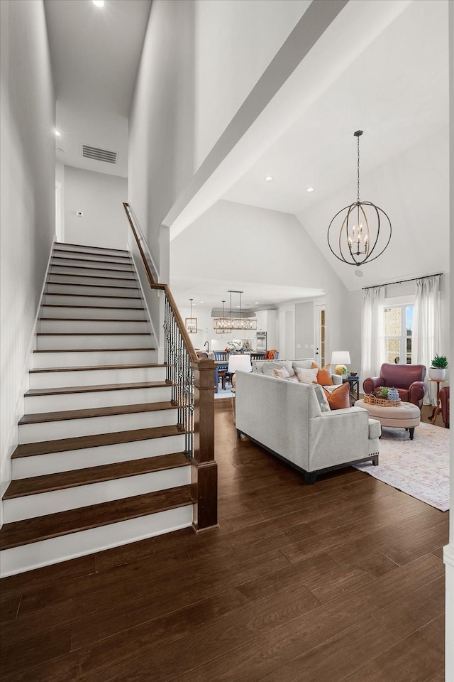 living area featuring high vaulted ceiling, stairway, dark wood finished floors, and visible vents