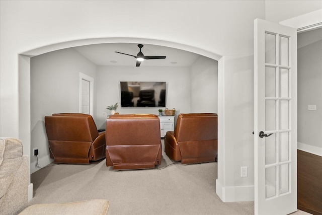 cinema with a ceiling fan, arched walkways, light carpet, and baseboards