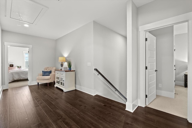 sitting room with attic access, baseboards, dark wood-type flooring, and an upstairs landing