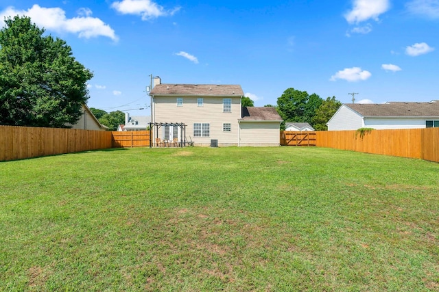 rear view of house with a yard and a fenced backyard