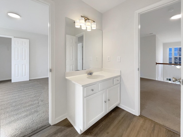 bathroom with wood finished floors, vanity, and baseboards