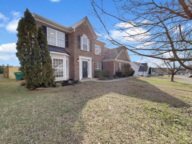 colonial-style house featuring a front lawn and brick siding