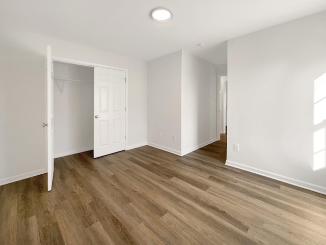 unfurnished bedroom with baseboards, dark wood finished floors, and a closet