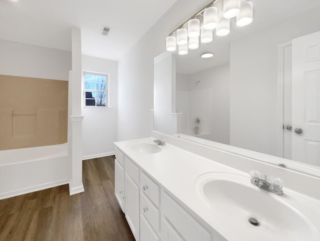 bathroom with double vanity, visible vents, a sink, and wood finished floors