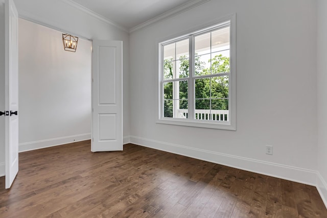 spare room with crown molding, baseboards, a chandelier, and dark wood-style flooring