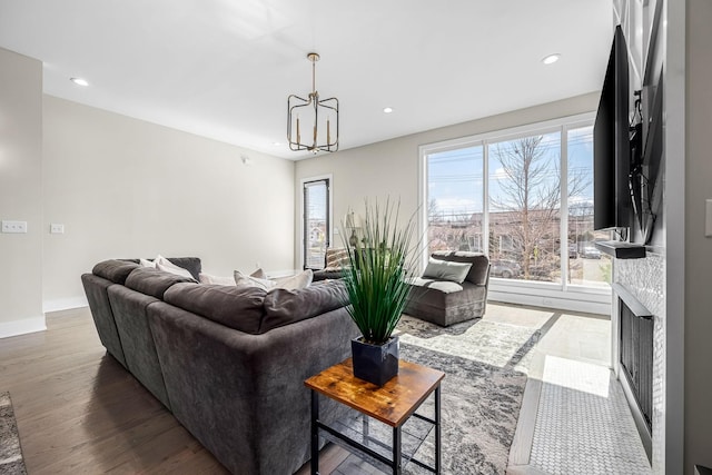 living area with baseboards, a fireplace with flush hearth, dark wood-style flooring, a chandelier, and recessed lighting