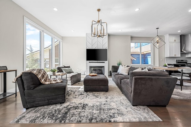 living room with dark wood finished floors, a glass covered fireplace, a notable chandelier, and recessed lighting