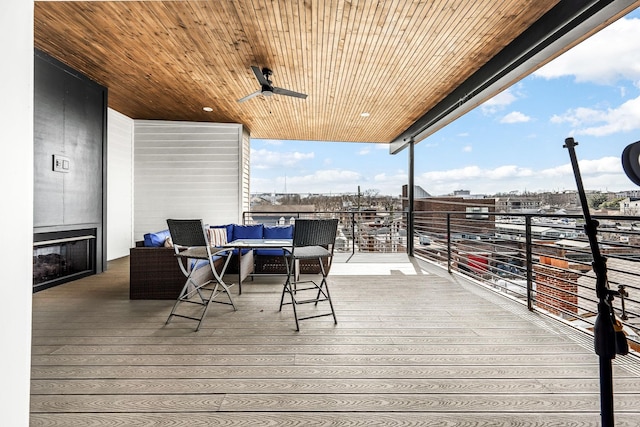 wooden terrace featuring ceiling fan and an outdoor living space with a fireplace