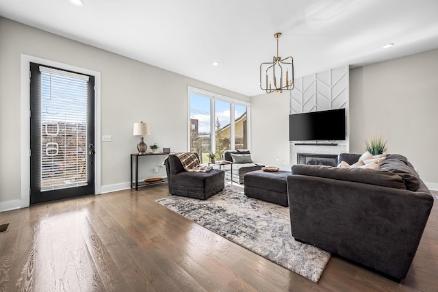 living area featuring an inviting chandelier, plenty of natural light, baseboards, and dark wood finished floors