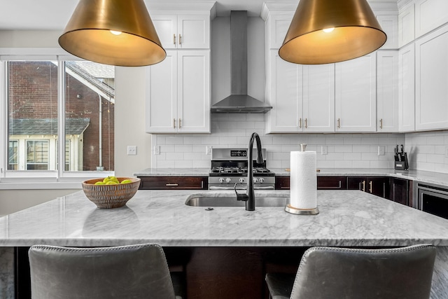 kitchen with white cabinets, wall chimney exhaust hood, and a breakfast bar