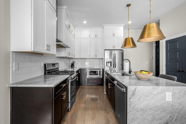 kitchen with hanging light fixtures, appliances with stainless steel finishes, a sink, and white cabinetry