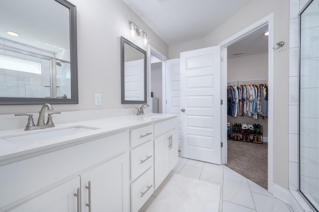 full bath featuring double vanity, a stall shower, a sink, and a walk in closet